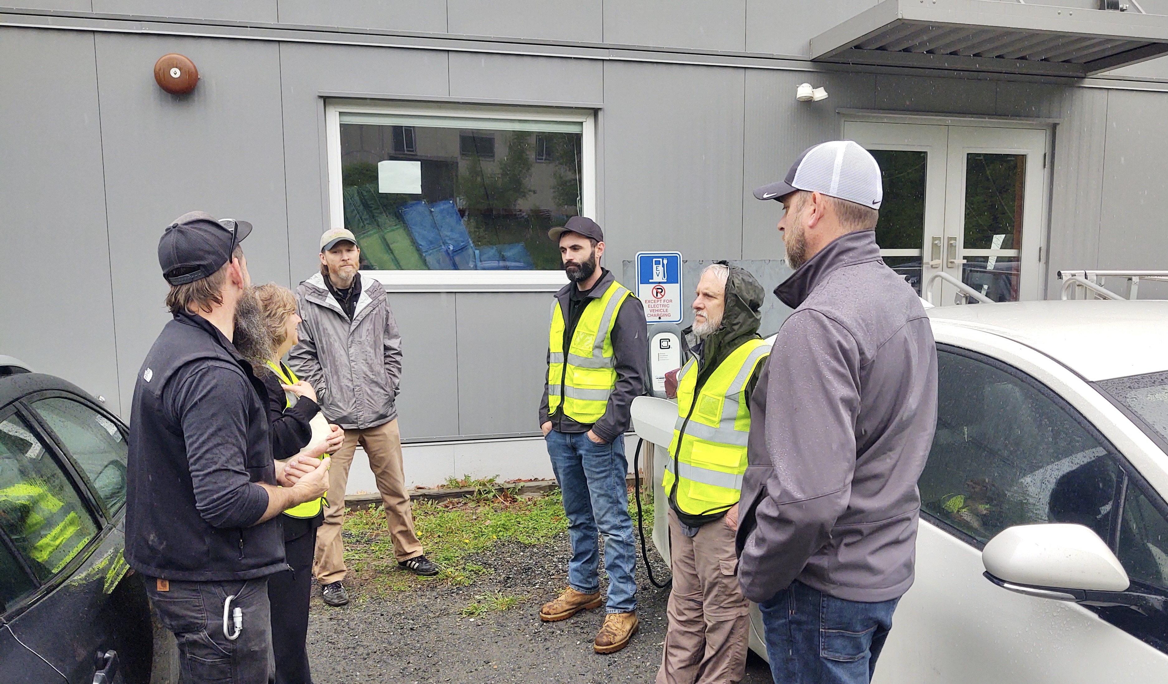 A group of people discuss the installation of an electric vehicle charger.