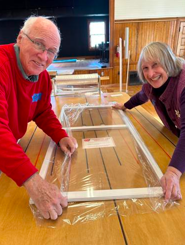Two people assembling a window frame as they volunteer with the organization Windowdressers.